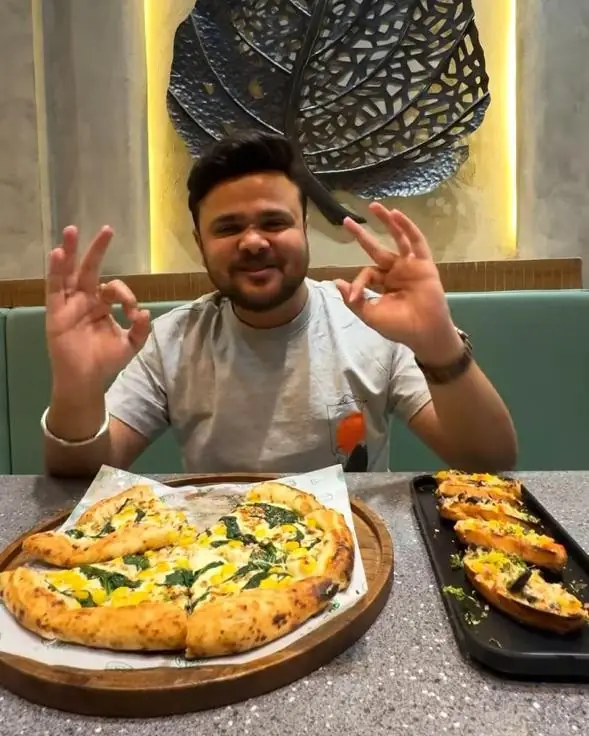 Guest giving a thumbs-up over a fresh pizza